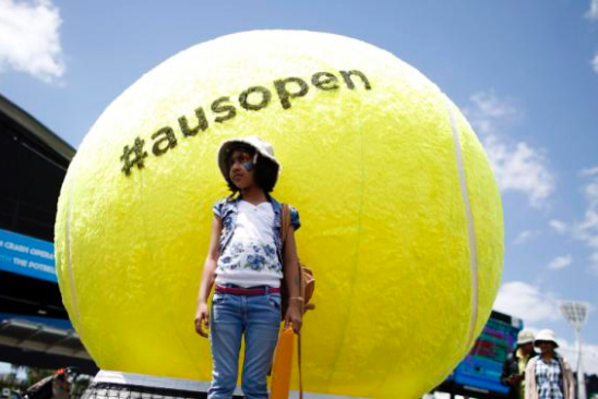 A girl poses for a photograph in front of a giant tennis ball located outside Rod Laver Arena at Melbourne Park January 17, 2015. The Australian Open tennis tournament begins on January 19. REUTERS/Issei Kato (AUSTRALIA - Tags: SPORT TENNIS)