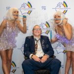 A man sitting down with two women standing beside him