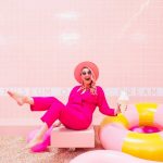 A women dressed in pink in a pink tiled room surrounded by pink objects