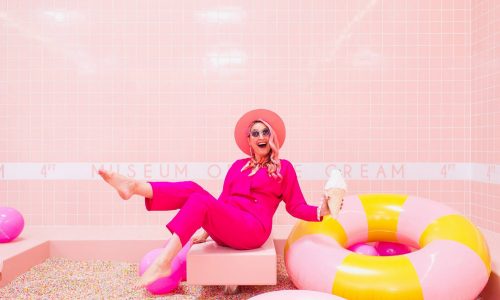 A women dressed in pink in a pink tiled room surrounded by pink objects