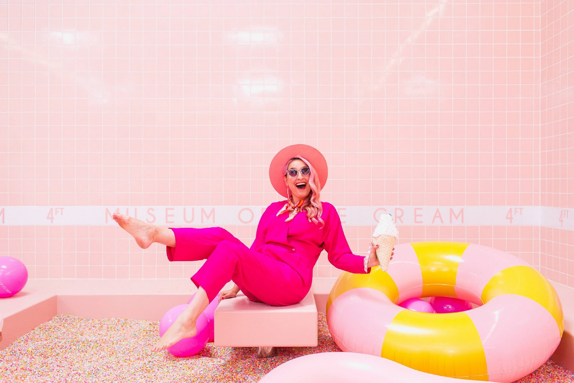 A women dressed in pink in a pink tiled room surrounded by pink objects