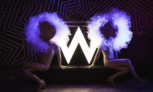 two models sitting in front of neon sign