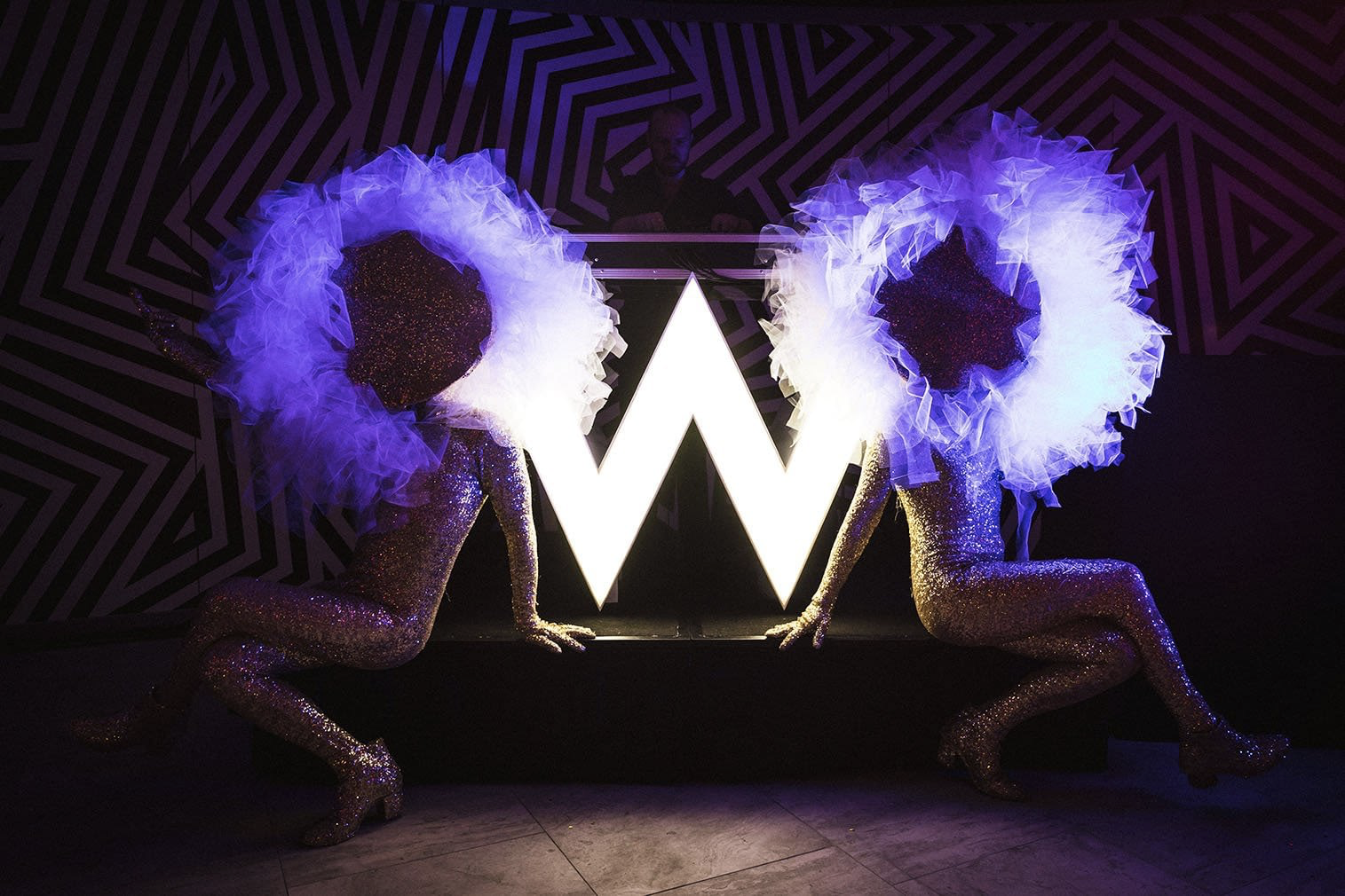 two models sitting in front of neon sign