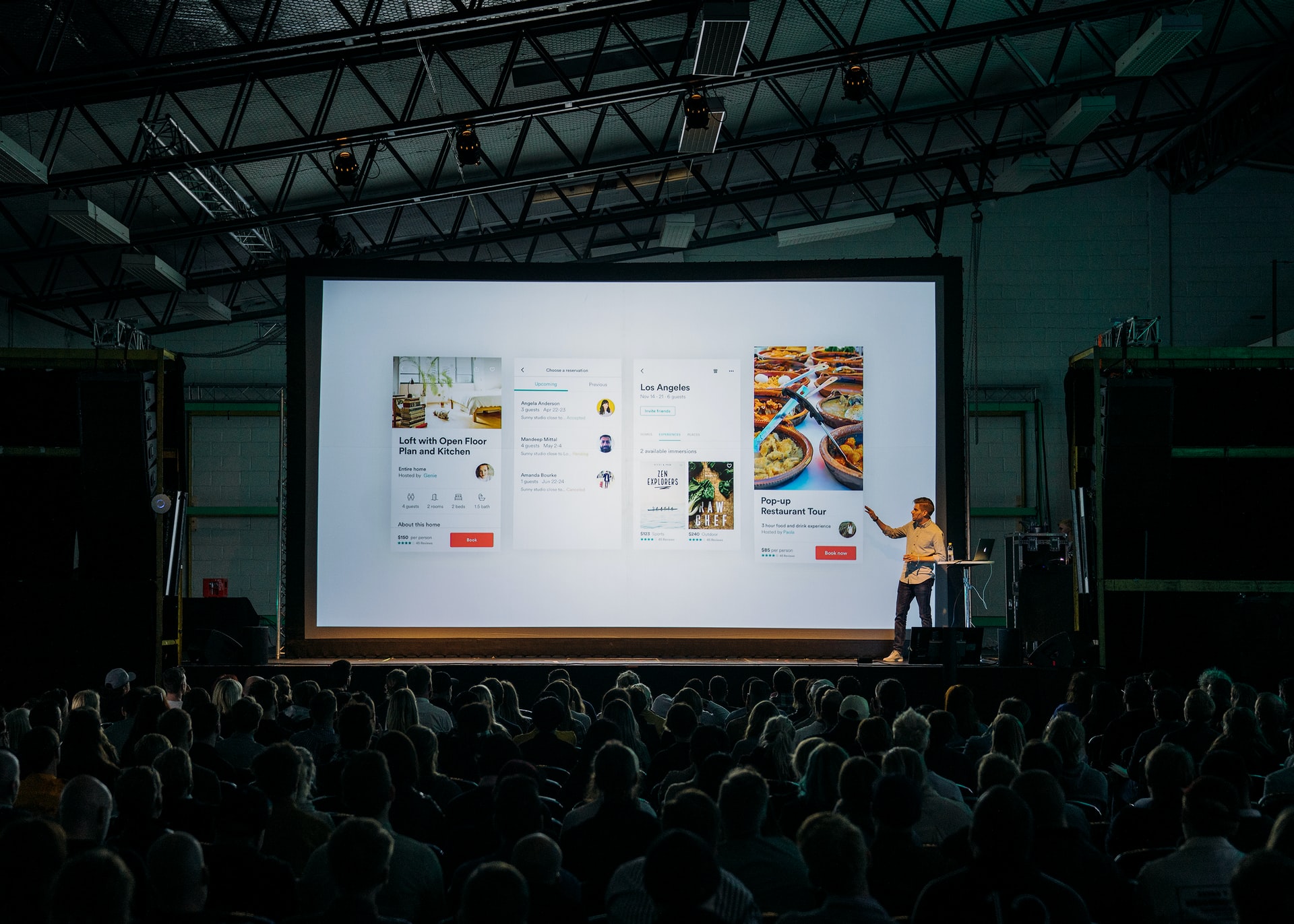 A man presenting to a live audience, both in person and virtually